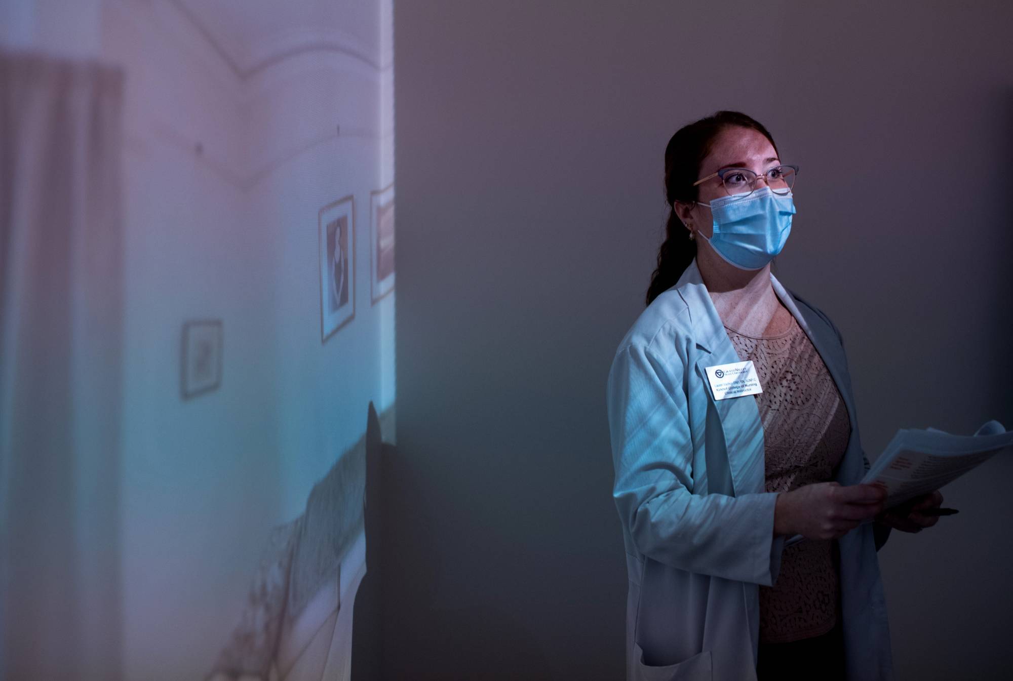 student in a mask looks into the light of a projector